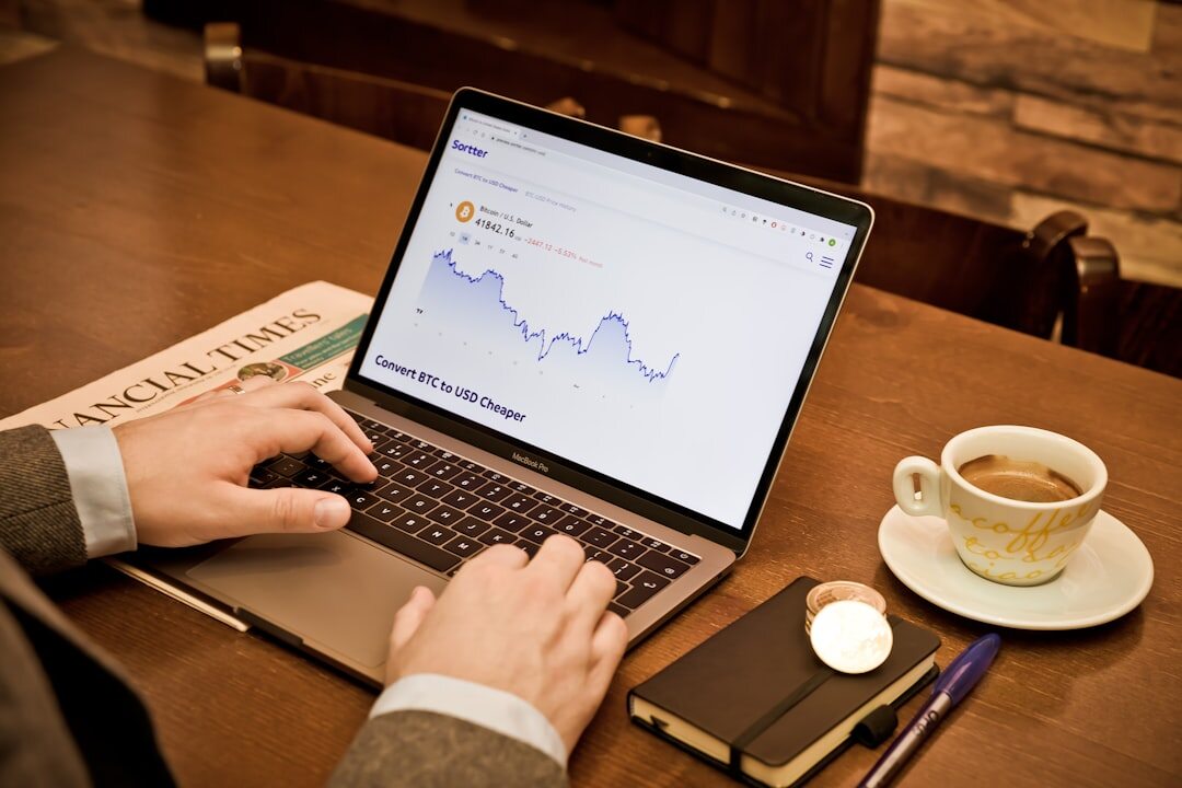 Close-up of hands typing on a laptop showing colorful market analytics charts